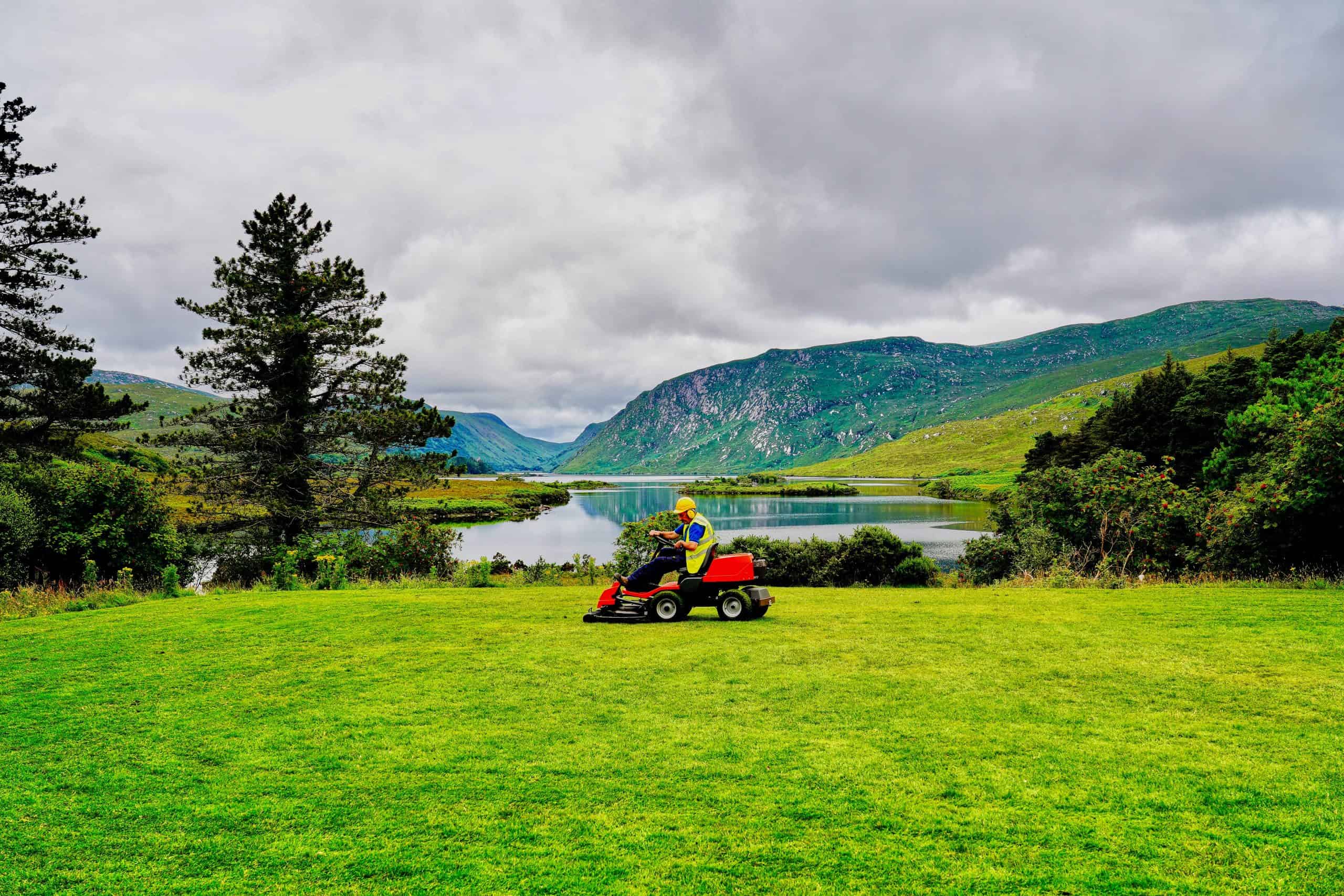 Man mowing lawn in front of lake